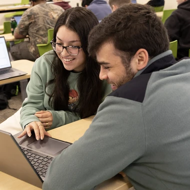 male and female student working on laptop