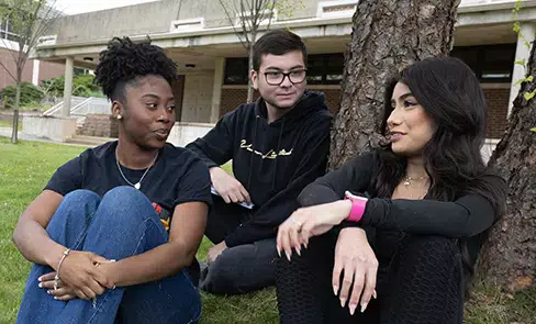 2 femal, 1 male student in campus courtyard