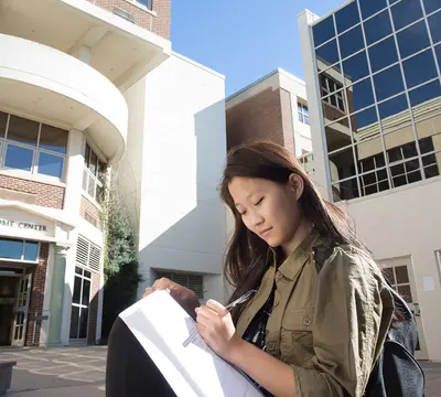 female student writing in notebook in front of RVCC