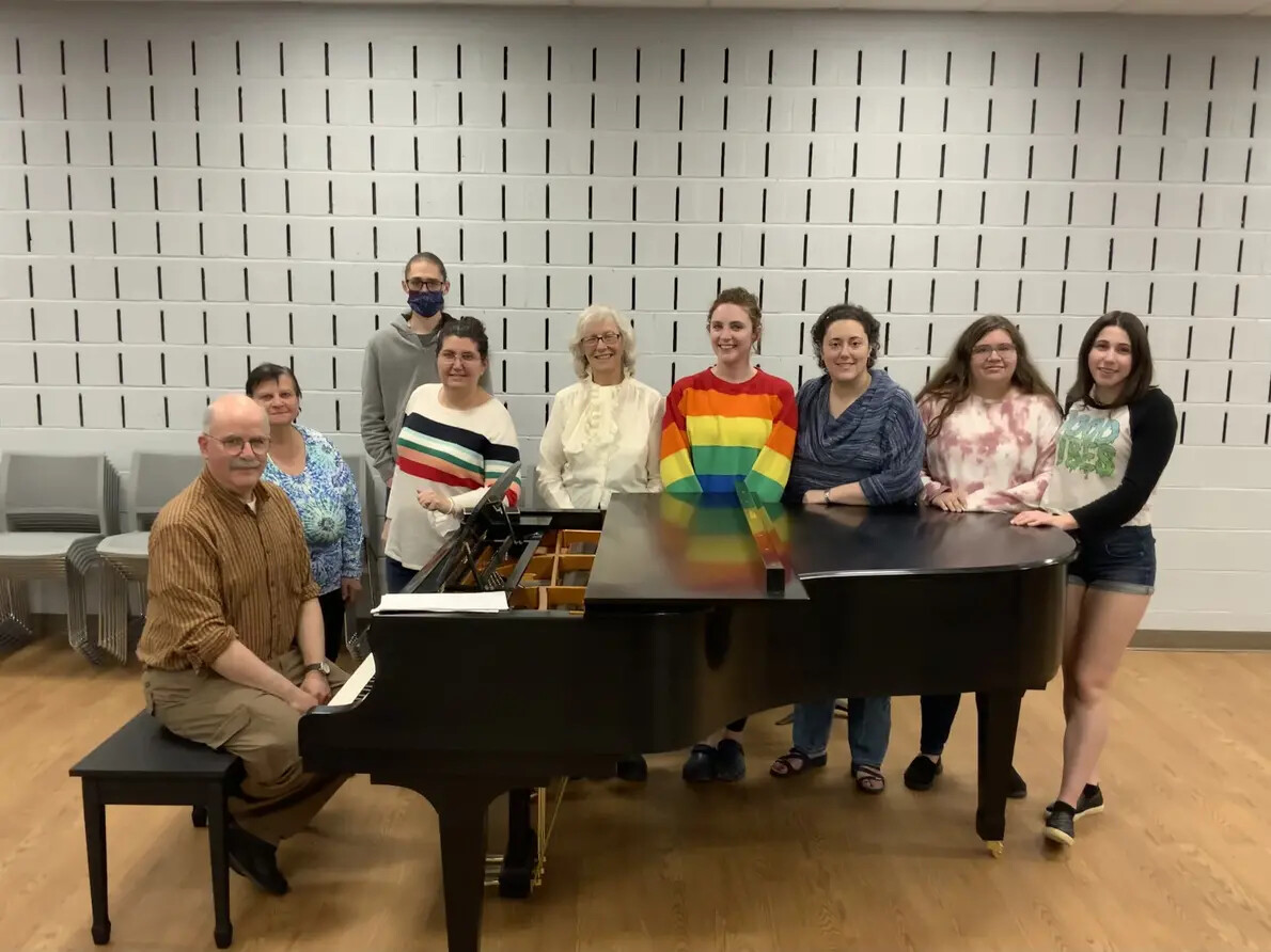 chorale members standing around piano