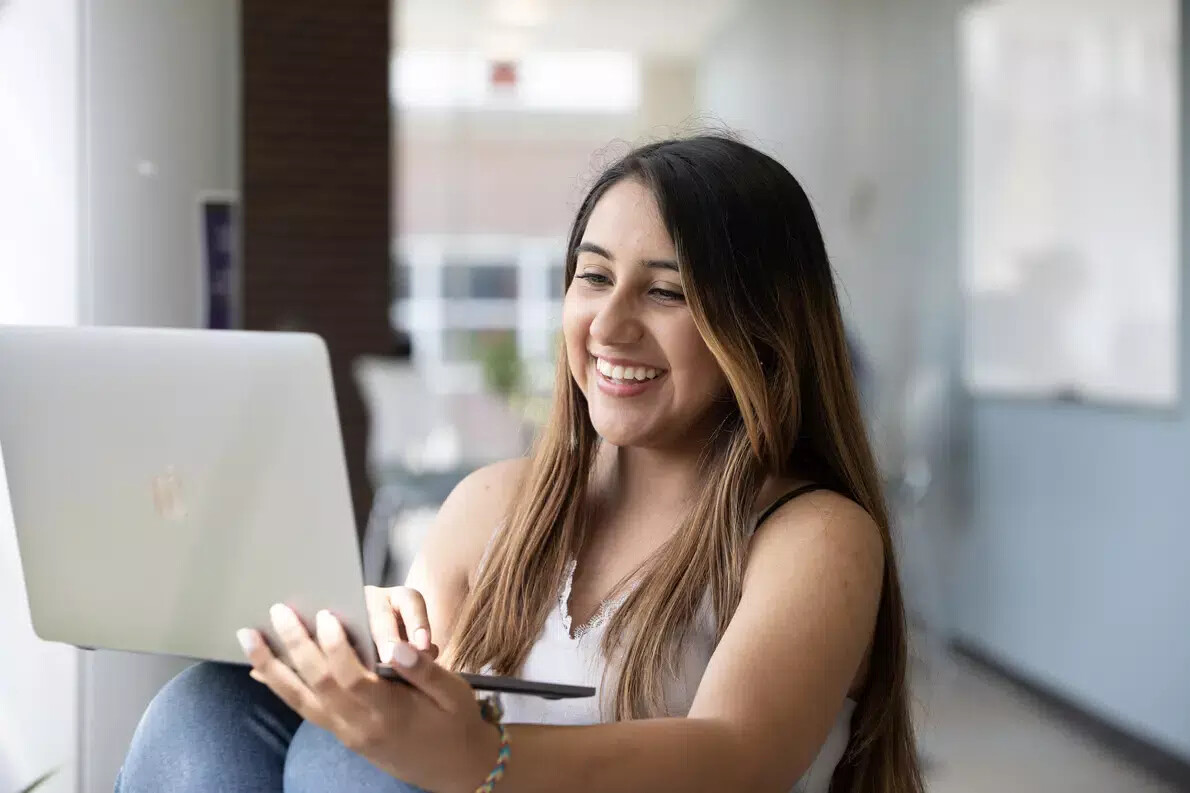 girl in sleeveless white top using laptop