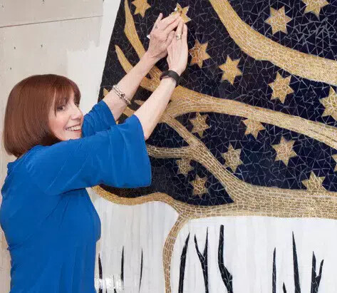 evelyn rauch with hands raised to artwork with stars