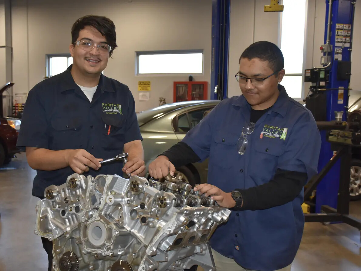 2 male students wearing glasses working on engine