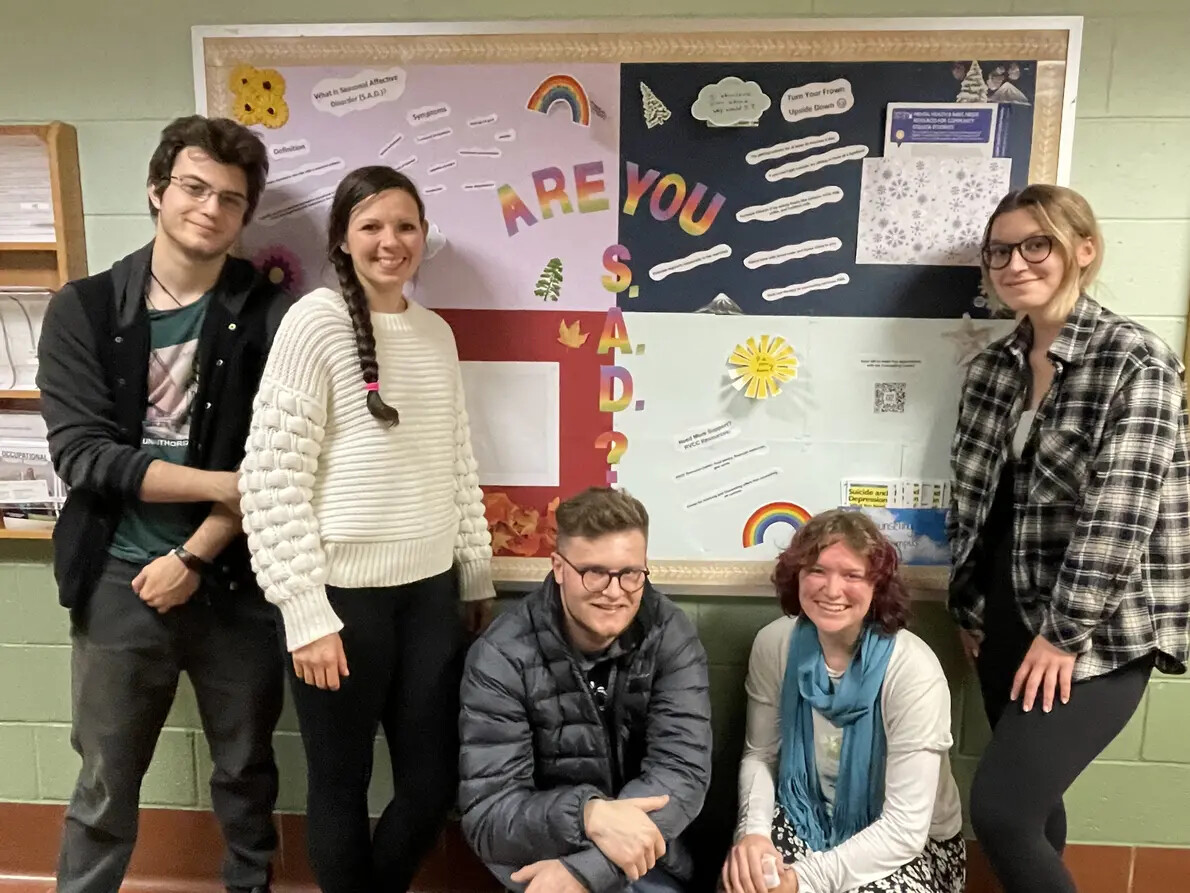 students in front of colorful bulletin board