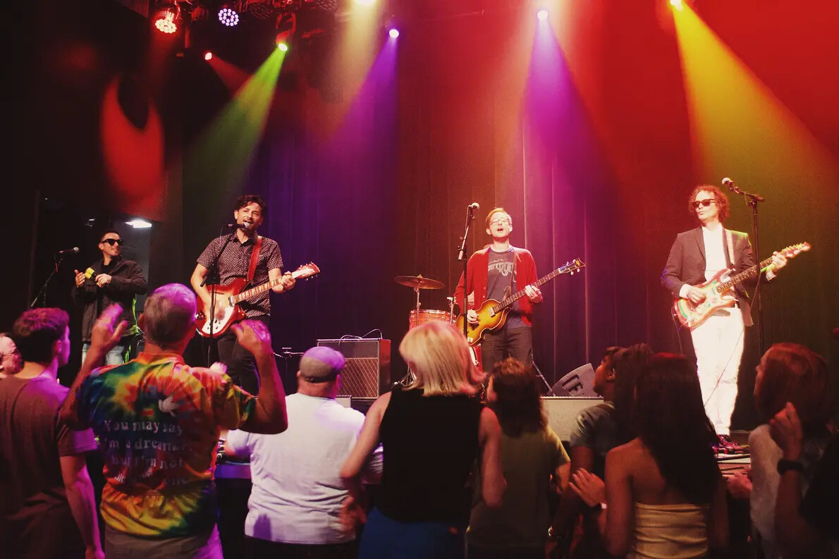 four musicians on stage with colored lights