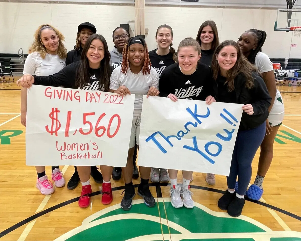 female students in gym holding giving day and thank you signs