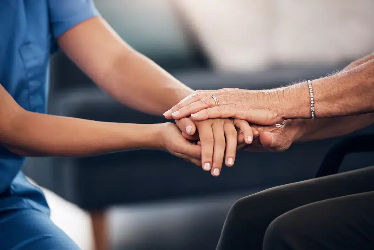 young nurse hands over older woman's hands with bracelet