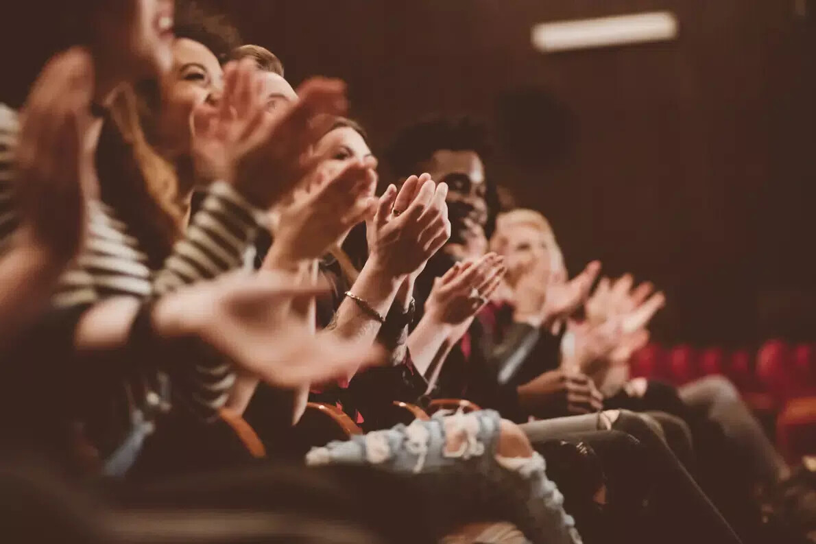 row of theatre audience members clapping