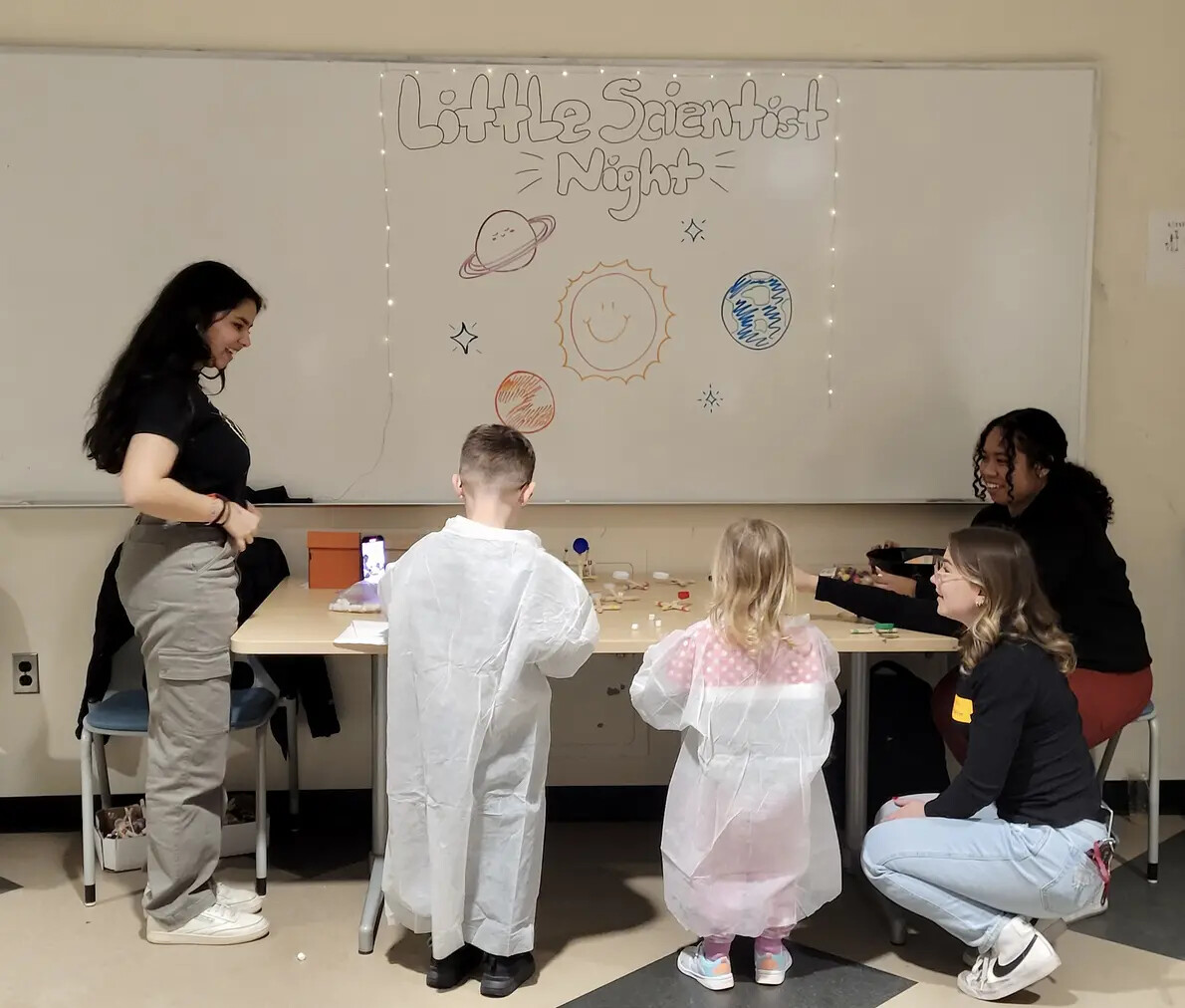 3 students and backs of 2 kids in labcoats