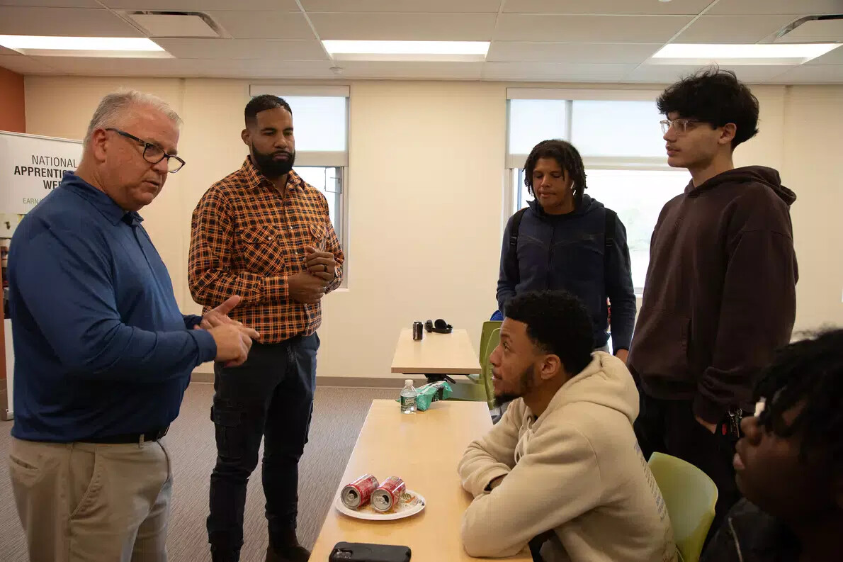 2 men on left talking to male students