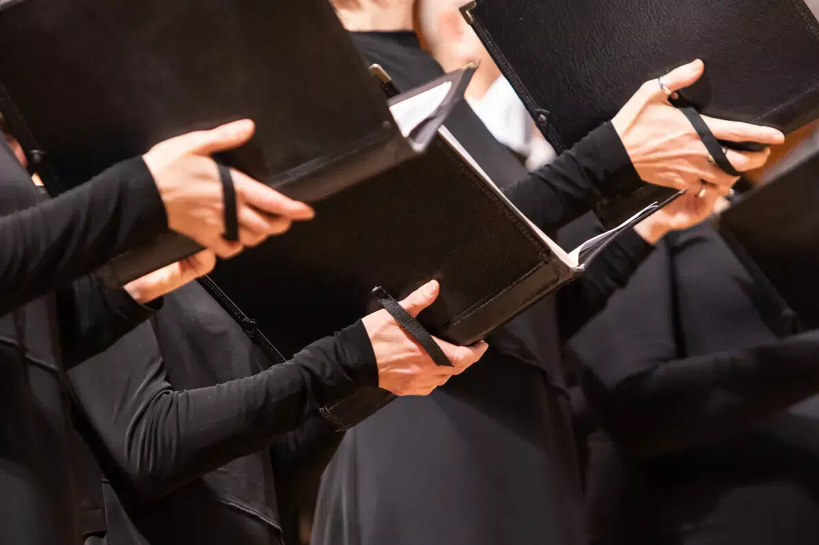 hands holding black choir books