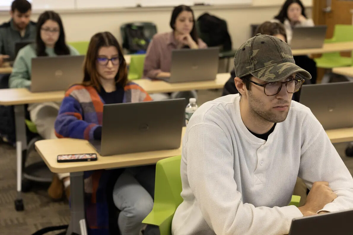 students at desks with laptops in classroom