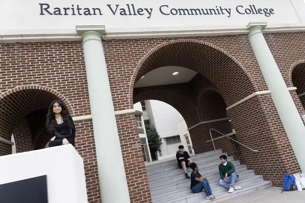 3 students sitting outside on steps under RVCC arches