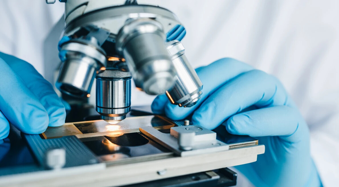 microscope with gloved hands