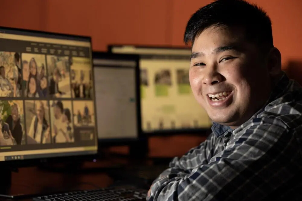 smiling male student with computer monitors