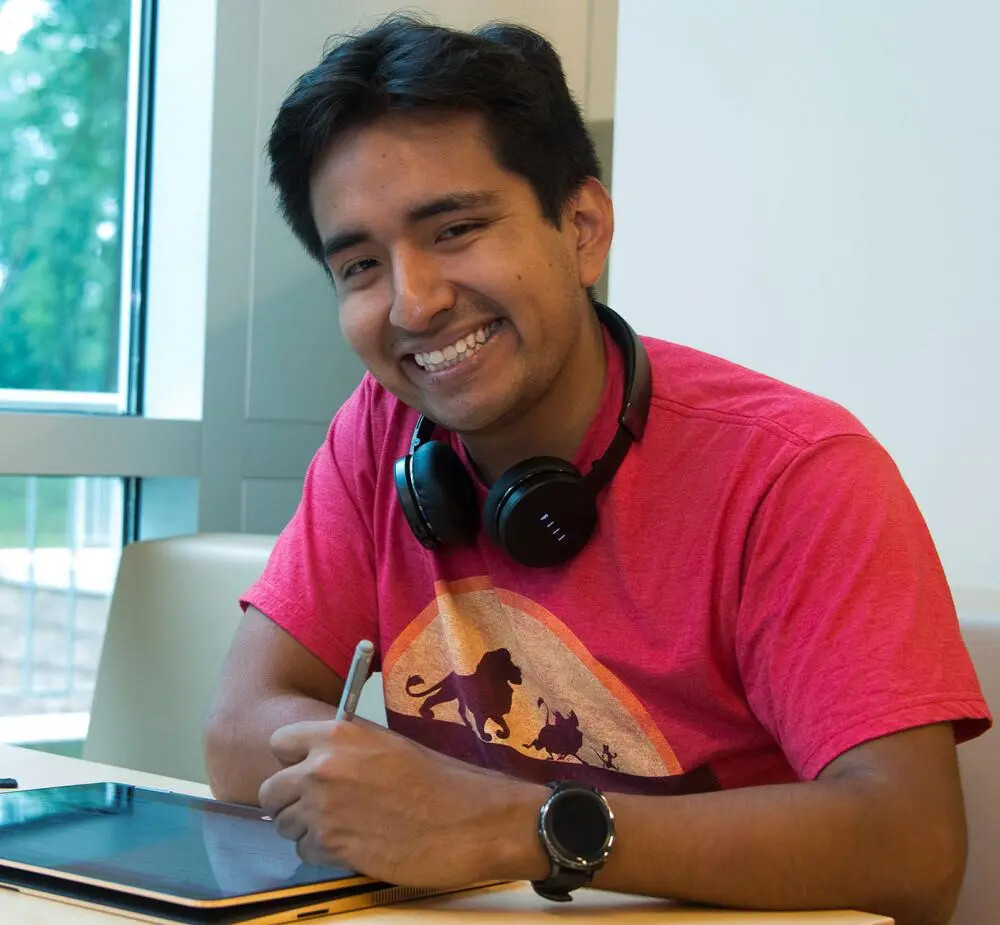 male student in red shirt writing with stylus on tablet