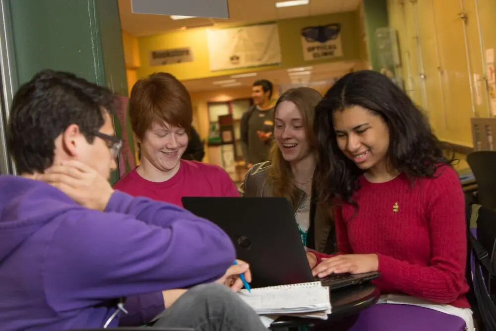 students huddled around laptop