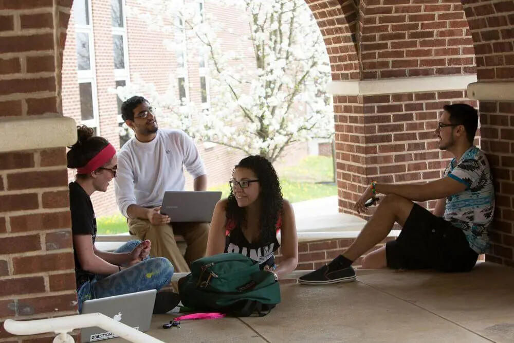 students sitting outside under under arches