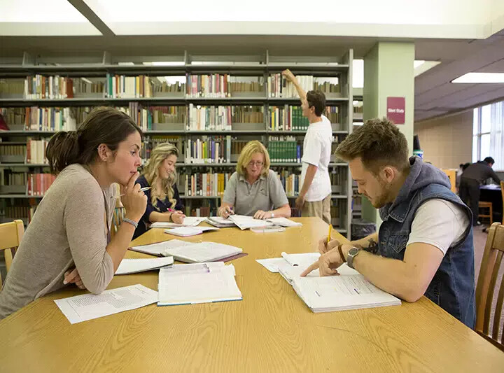 students studying around table in library