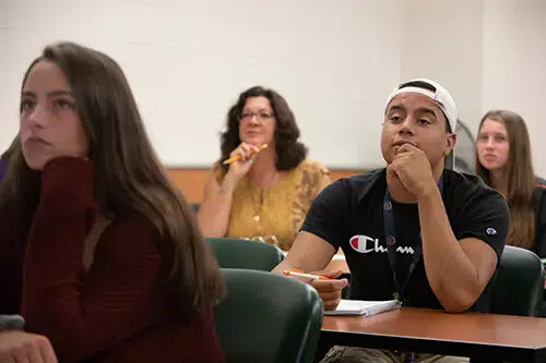 three female students and one male with baseball cap in classroom