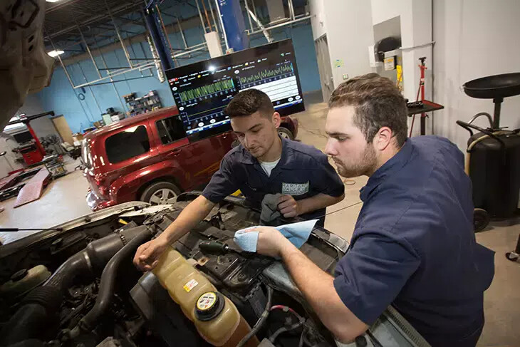 two auto tech students working on car