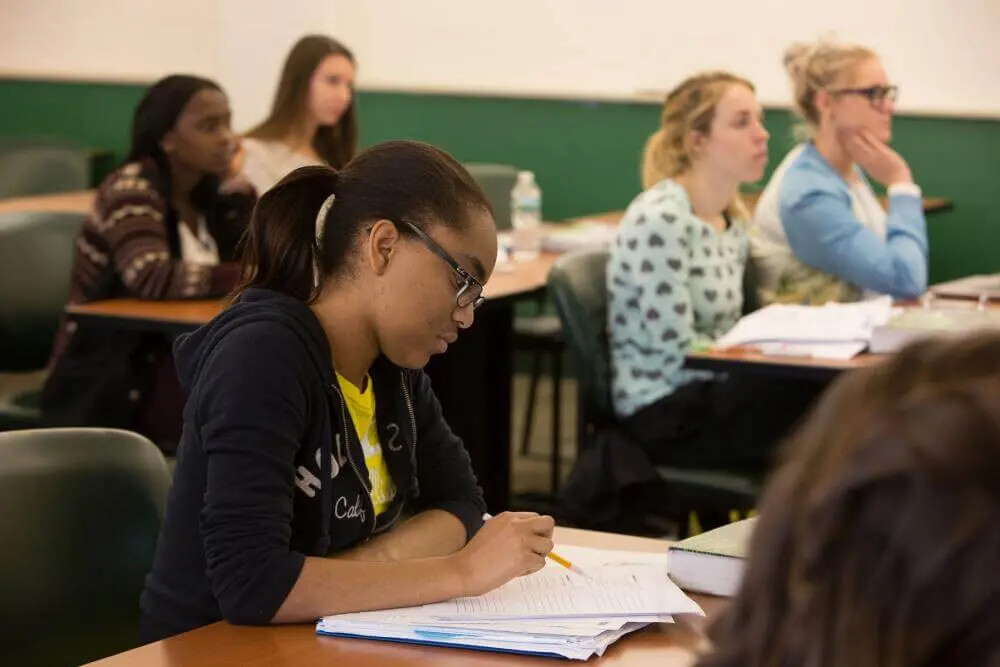 femal student writing in classroom with others