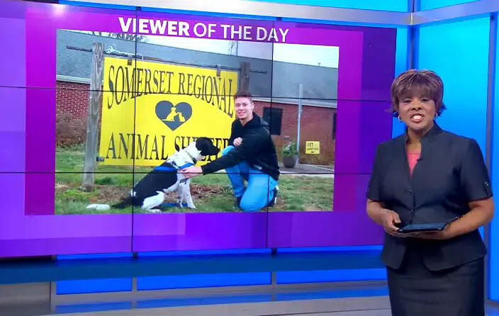 male student kneeling next to dog and della crews