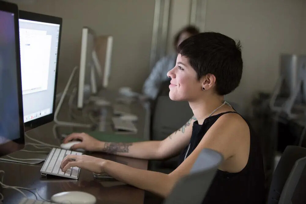 girl in sleeveless dark top on computer in lab