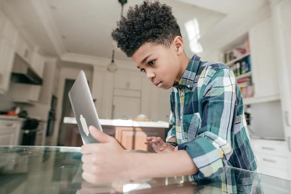 boy in plaid shirt holding his laptop