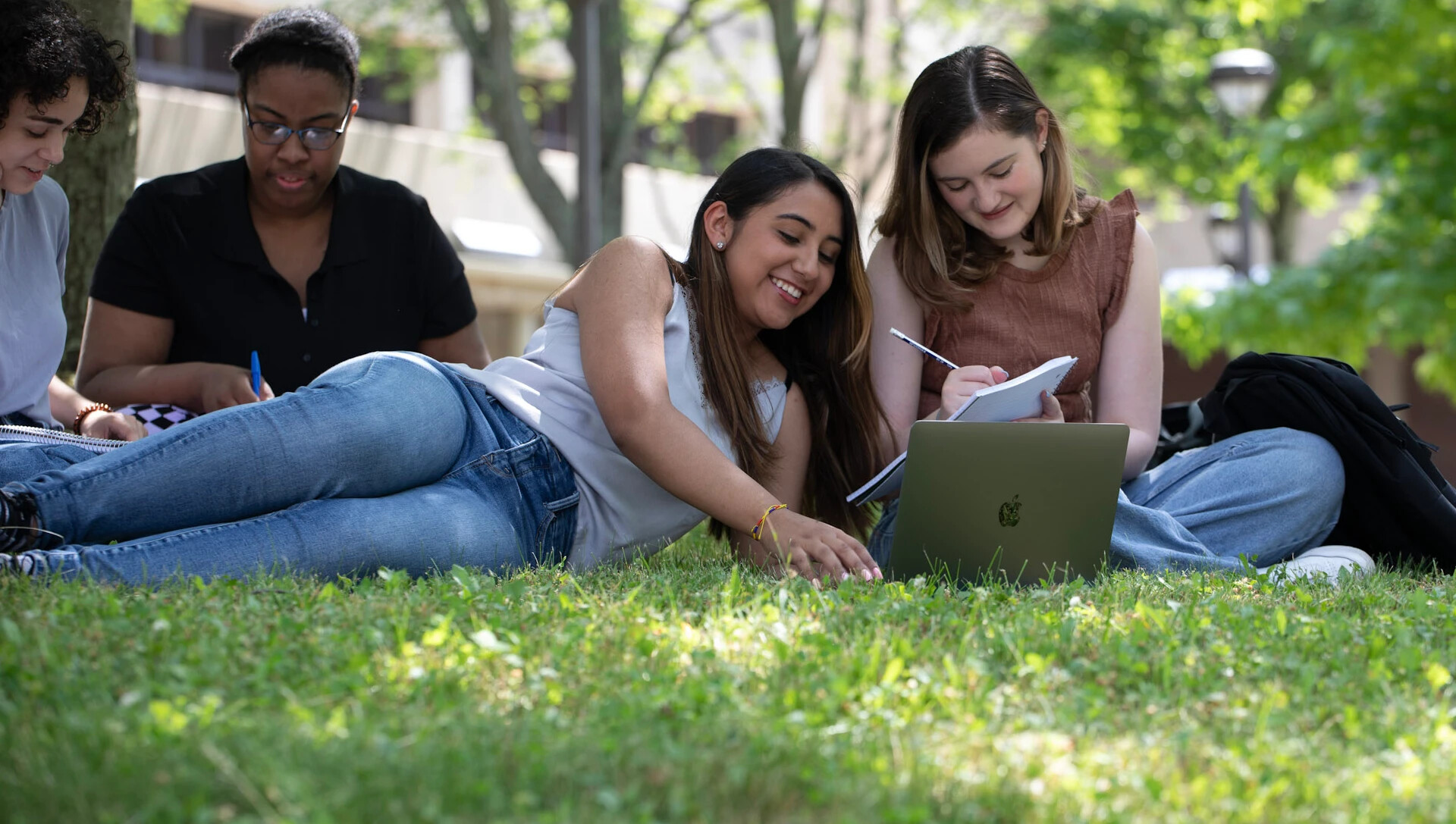 4 students working on laptops in courtyard