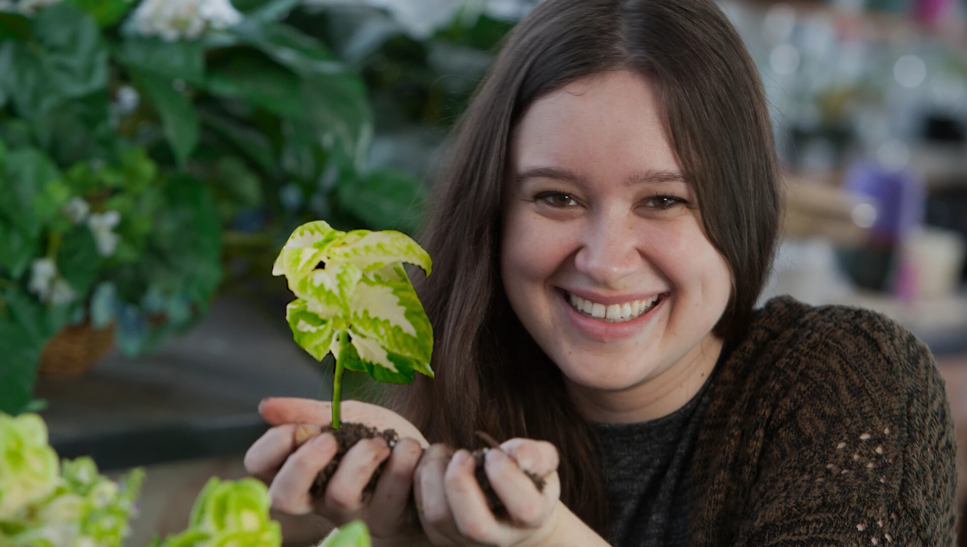 female student in greenhouse holding plants