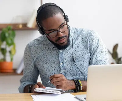 student taking notes at computer