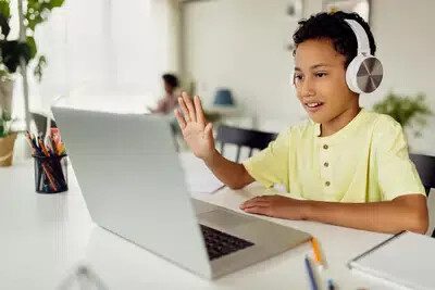 boy in yellow shirt with white headphones with laptop