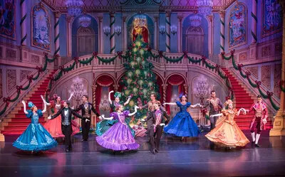 dancers in ballgowns with christmas tress