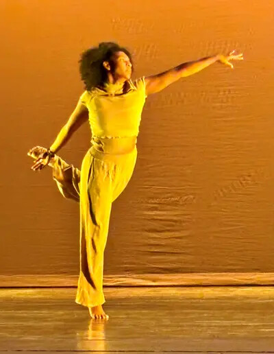 dancer in yellow outfit on one foot