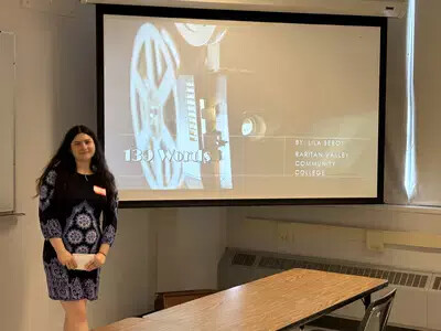 girl in dress standing next to screen with presentation