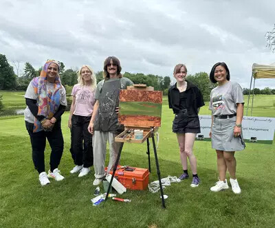 5 people outside with artist canvas and painting