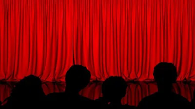 red curtain and backs of audience members heads