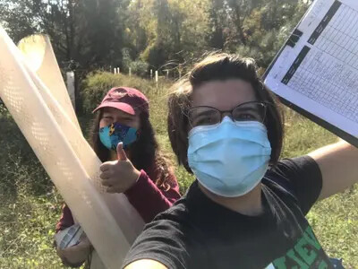 2 masked students working outside on tree project