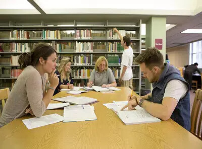 students studying around table in library