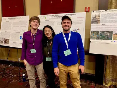 3 students in front of posters at conference